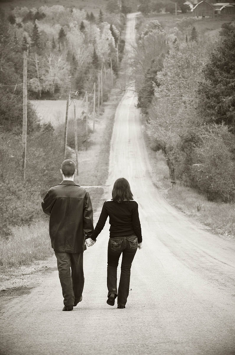 Walking hand in hand down steep country road for country themed Peterborough engagement photography session