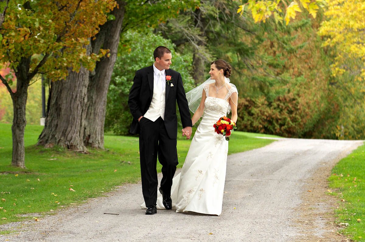 Bride and Groom stroll happily along country road at Eganridge wedding