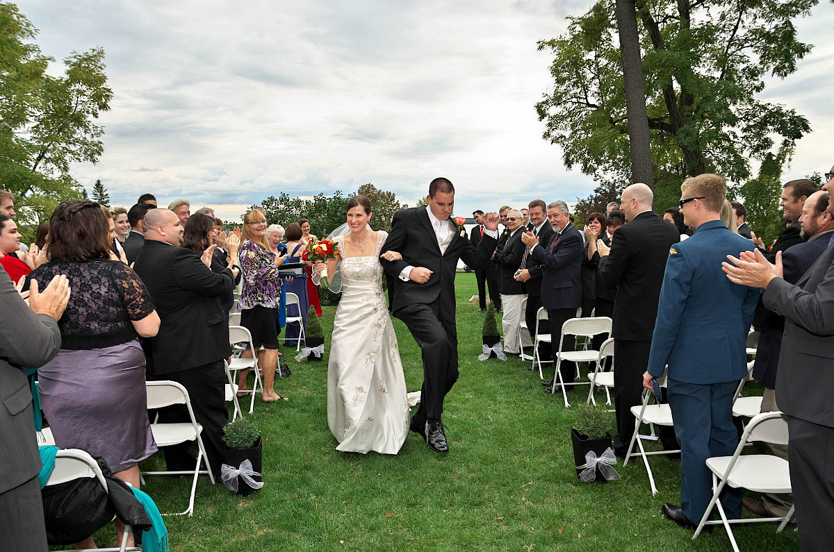 Dynamic groom and bride walk together down ceremony aisle as husband and wife at Eganridge wedding