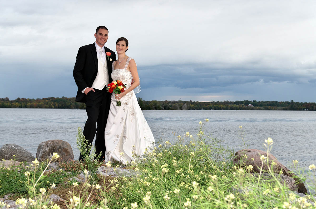 Bride and groom with wildflowers and lake at Eganridge wedding