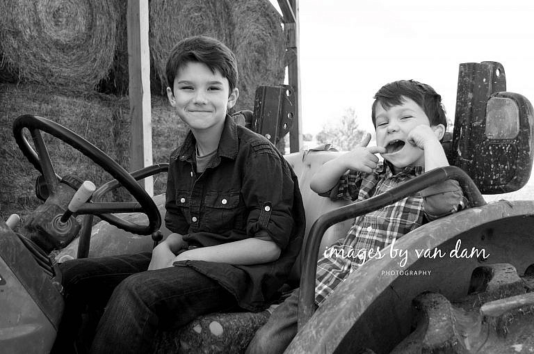 stayner photographer barrie photographer family portraits wasaga photographer collingwood photographerTwo brothers Make Funny Faces while sitting on a John Deere tractor