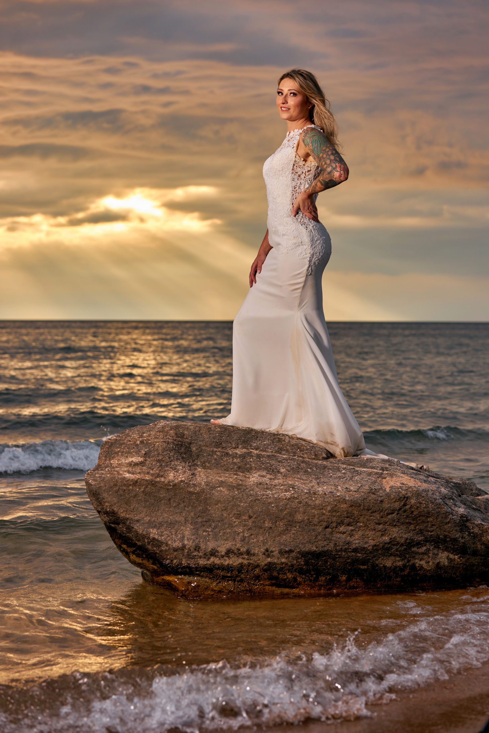 Bride Standing on Rock in water at Georgian Bay Beach at Sunset During Trash the Dress Session