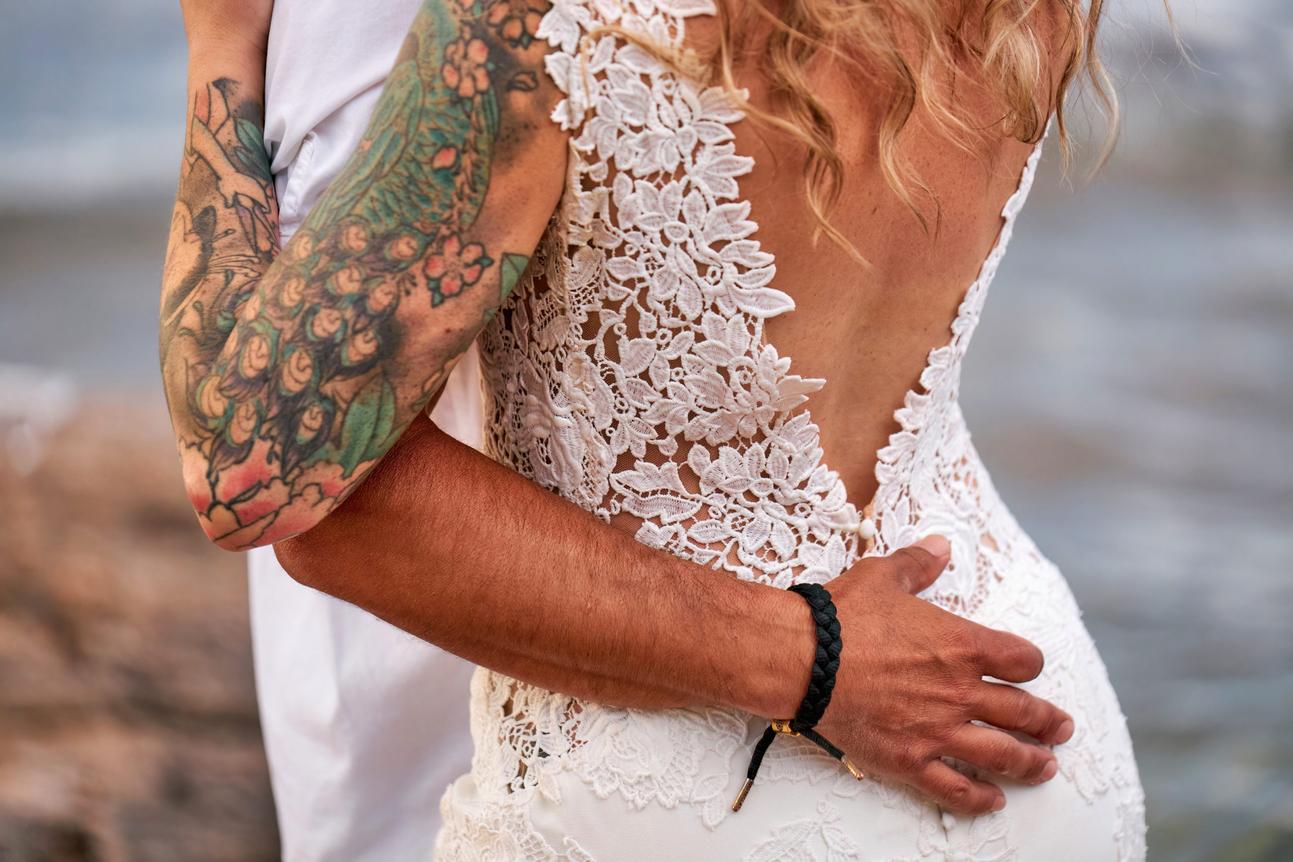 Close up of a Groom's Arm wrapped tightly around the small of his wife's back at a Rock the Dress session