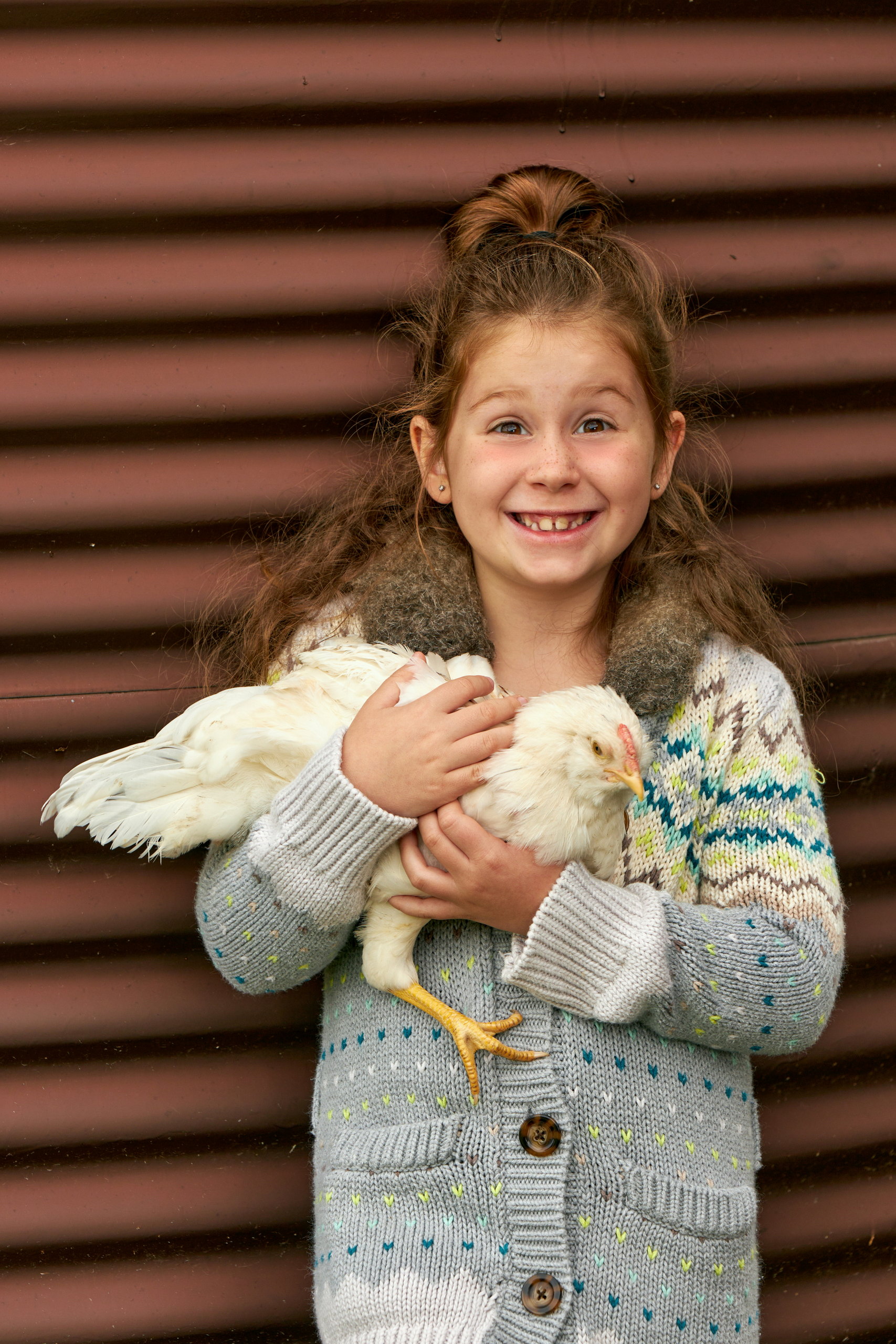 Happy young girl proudly holds her pet chicken at Kawartha Lakes family portrait session