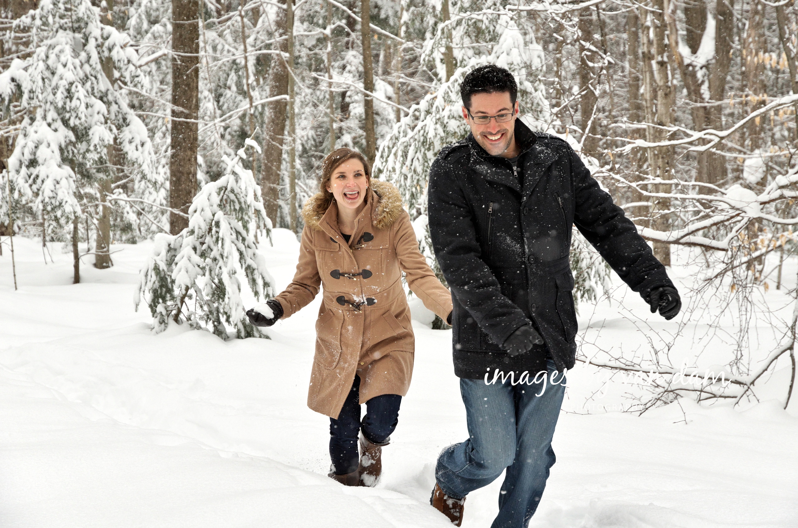 A young woman chases her fiancé with a snowball in a wintery forest