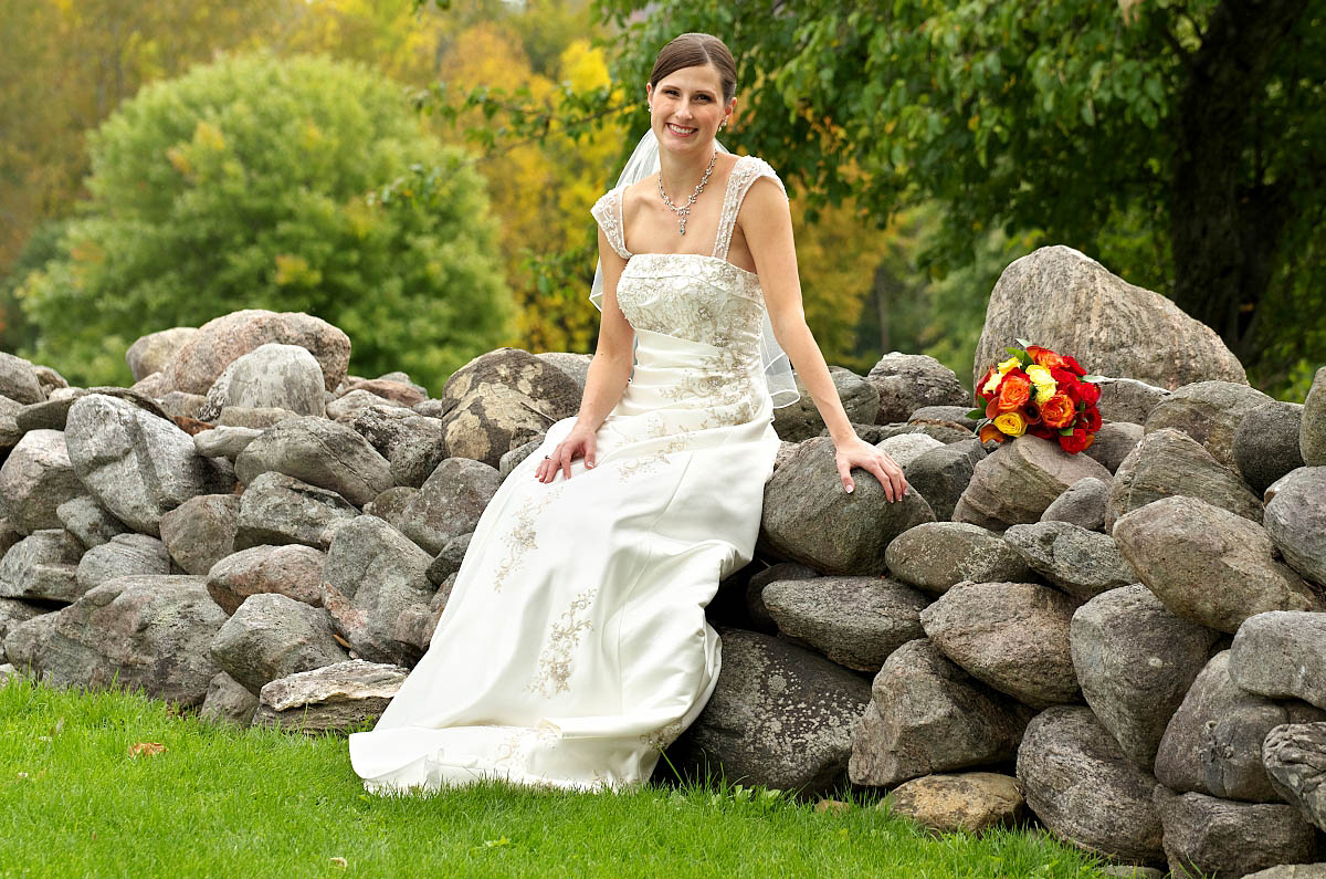Beautiful bride sitting on old stone wall at EGanridge wedding near Bobcaygeon
