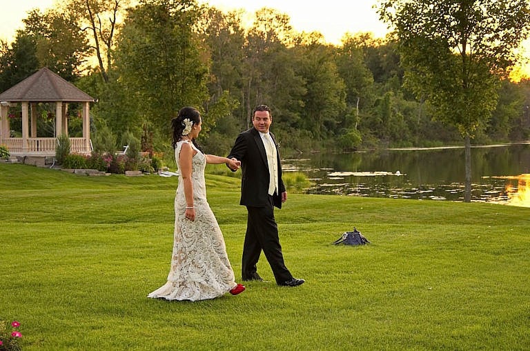 bride and groom stroll by pond at sunset at caledon wedding at Royal ambassador
