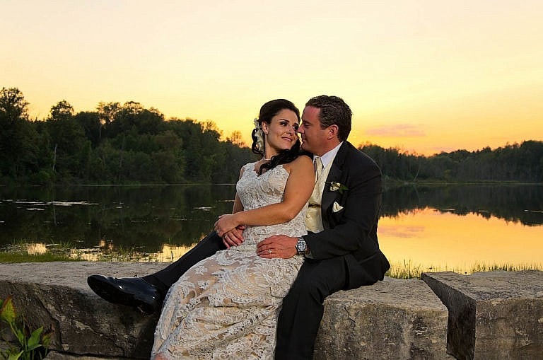 bride and groom on rocks in front of pond at sunset at caledon wedding at Royal ambassador