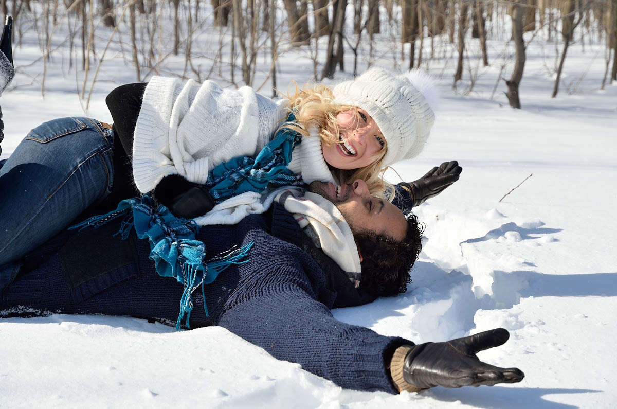 happy couple frolicks in snow during engagement photography session on bruce trail, at top of blue mountain in collingwood