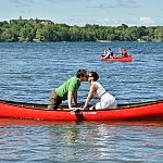 bride and groom kissing in red canoe at summer camp wedding