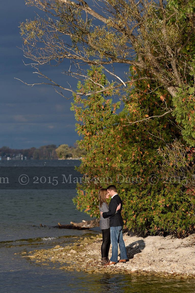 Couple kissing on shores of Lake Couchiching at Orillia engagement session at Leacock Museum