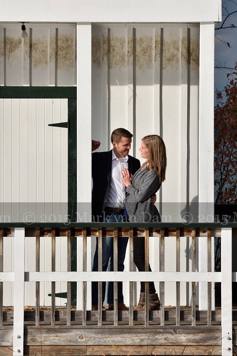 Stylish couple leans against boathouse door at Leacock Museum engagement photography session