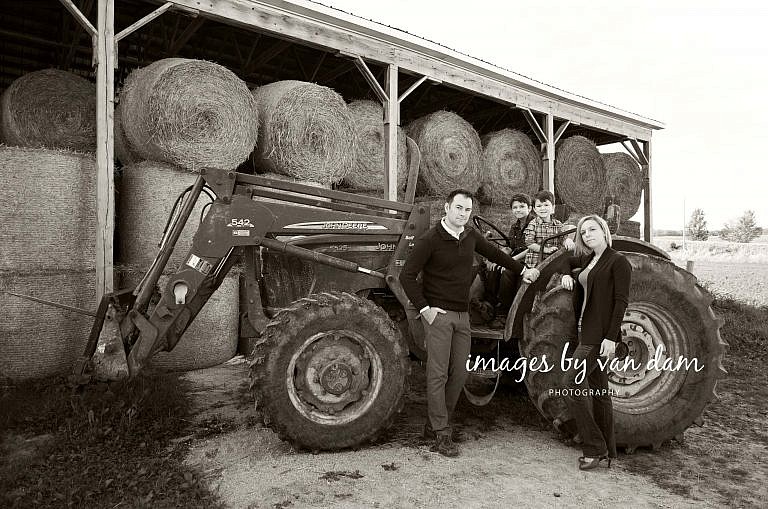 Young Family Poses in front of Tractor and hay bales stayner photographer barrie photographer family portraits wasaga photographer collingwood photographer