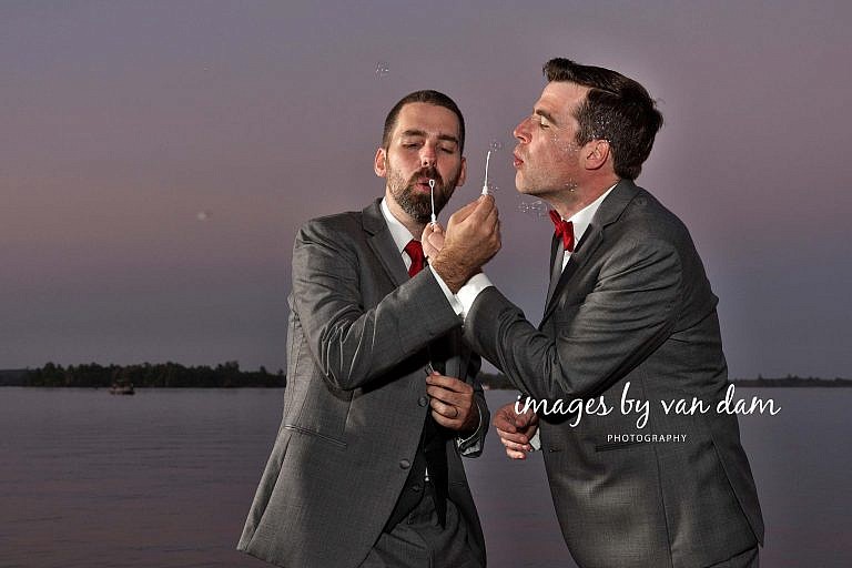 Two Grooms Blow Bubbles on Dock at Dusk