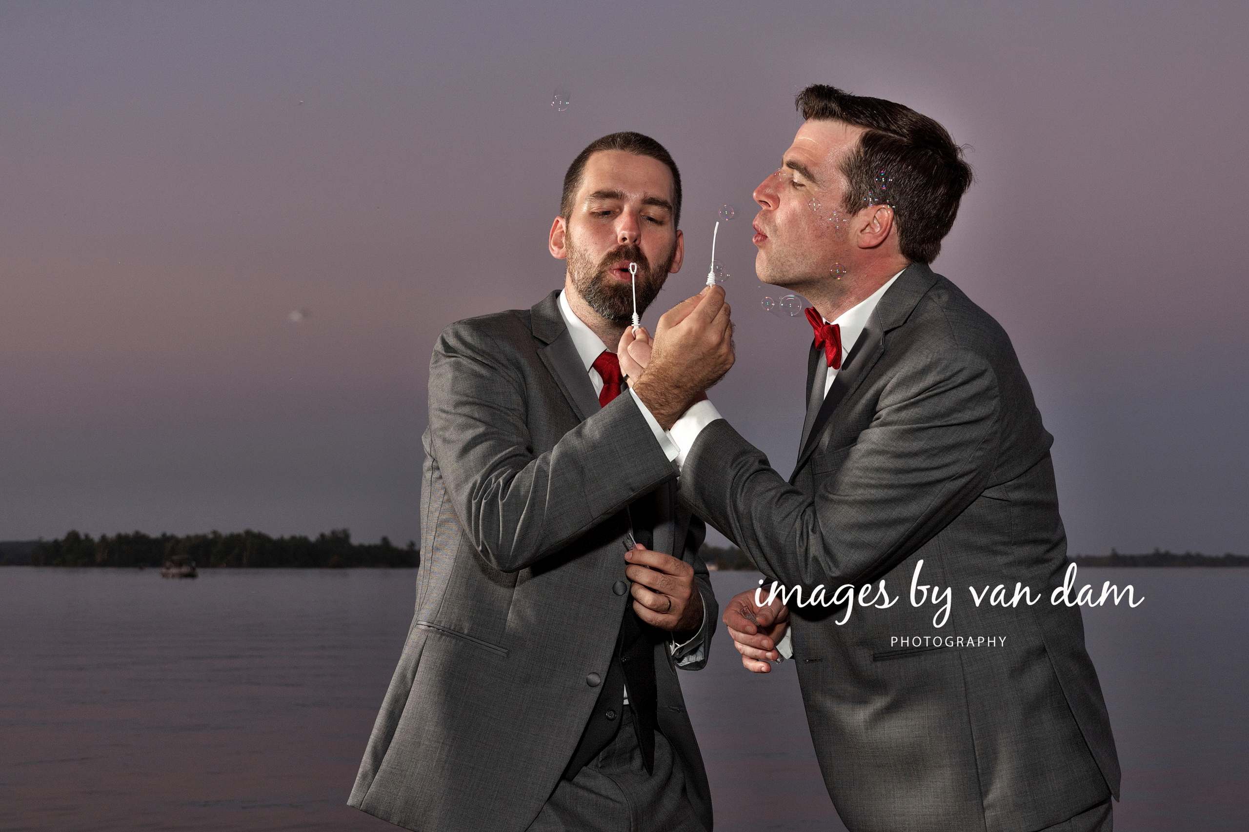Two Grooms Blow Bubbles on Dock at Dusk