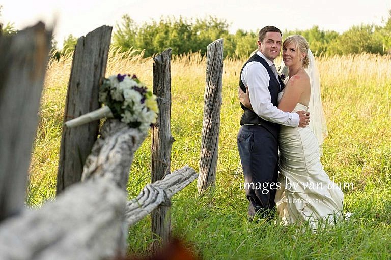 bride and groom at abandoned orchard with bouquet on split rail fence near Lora Bay wedding