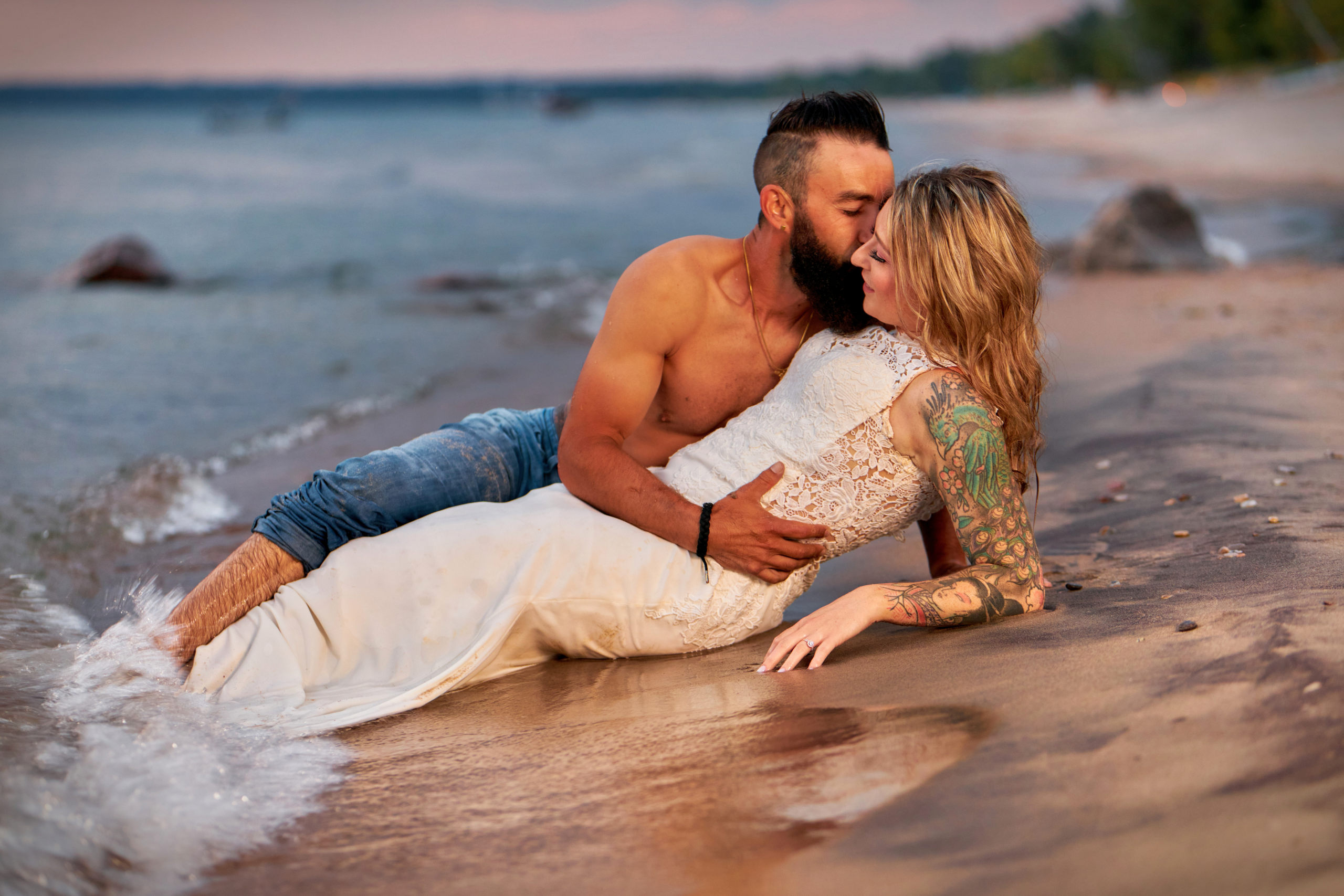 Groom Kisses Bride in shore break on Georgian Bay beach during evening Trash the Dress Session in Tiny, Ontario