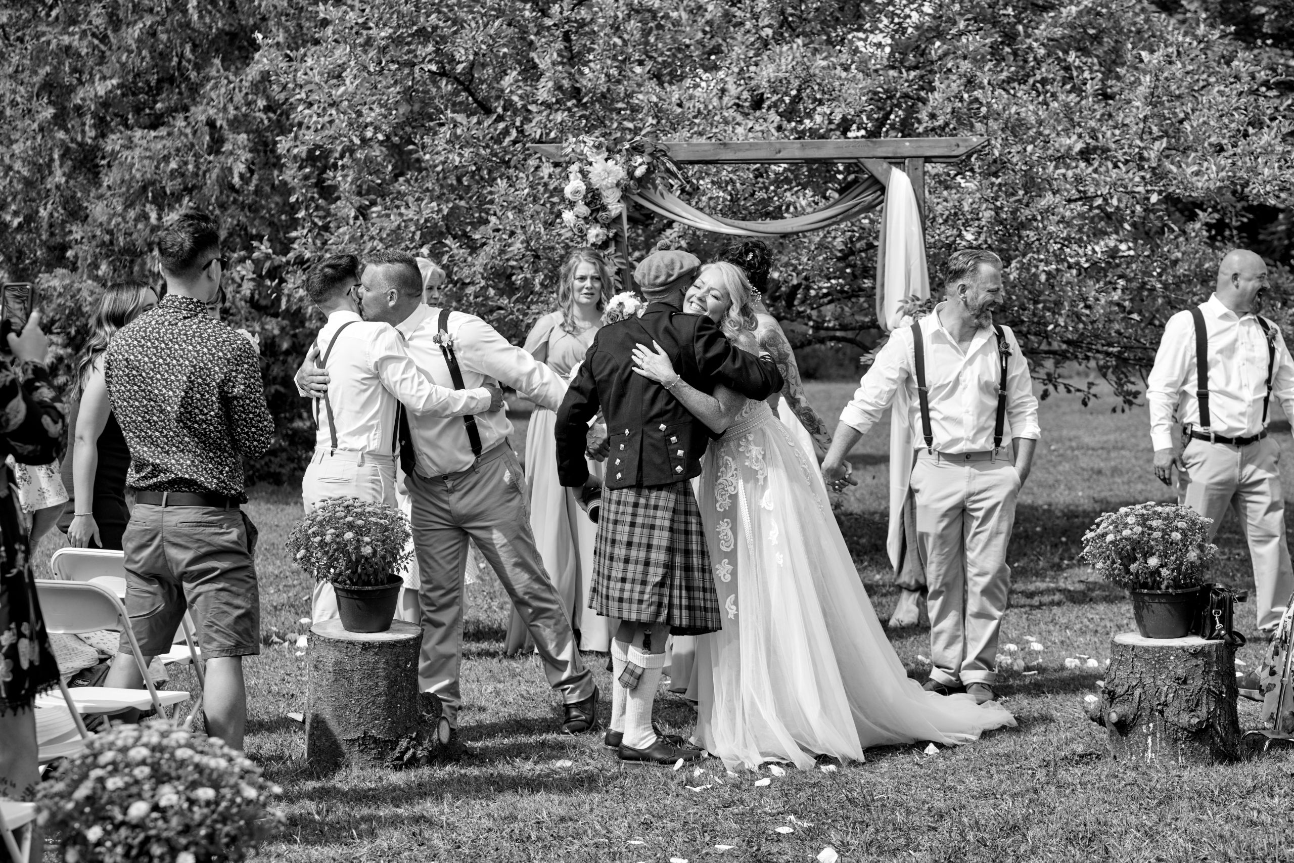 A newly married couple embrace loved ones immediately after ceremony at outdoor wedding