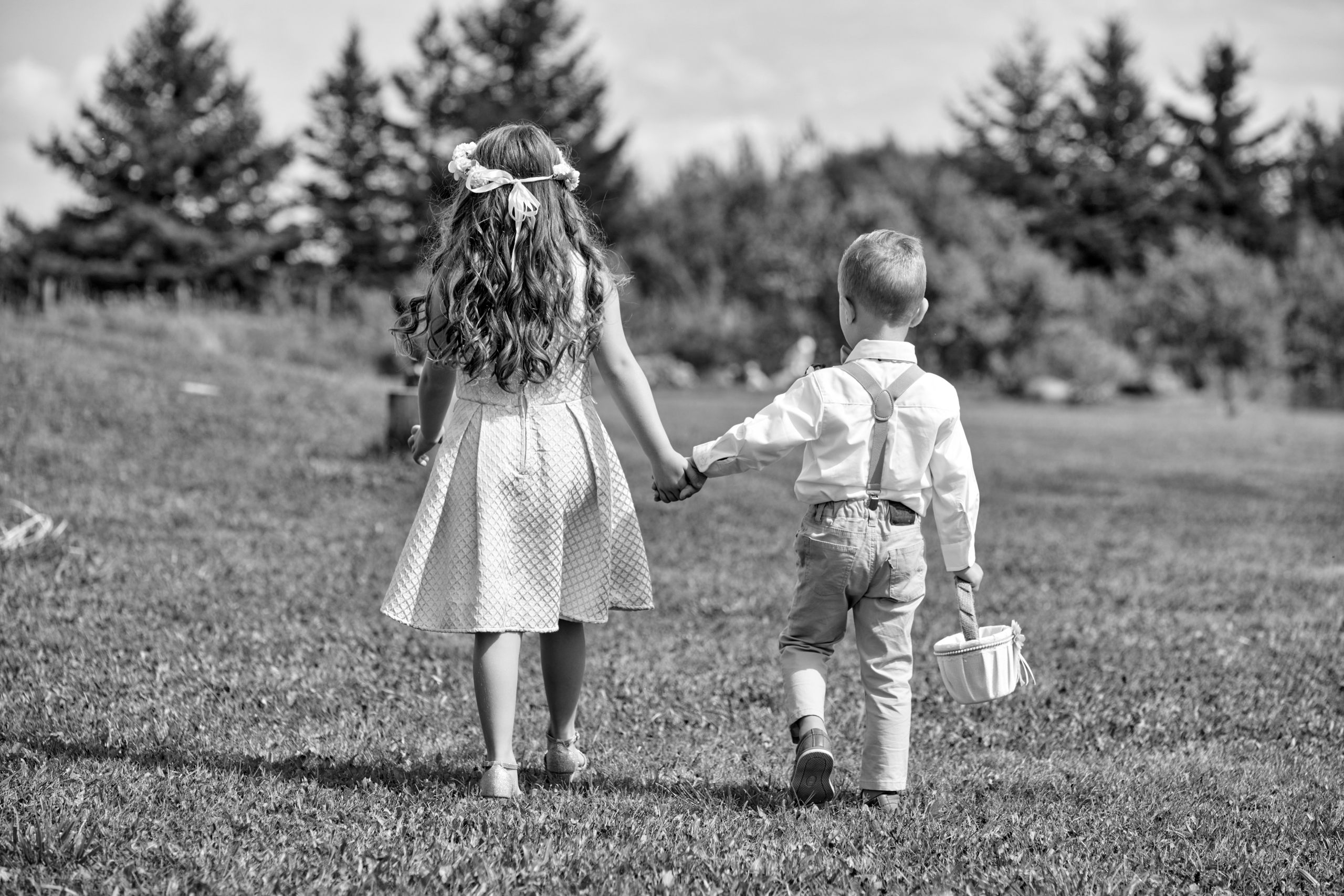 Shot from Behind of young flower girl and ringbearer walking hand in hand
